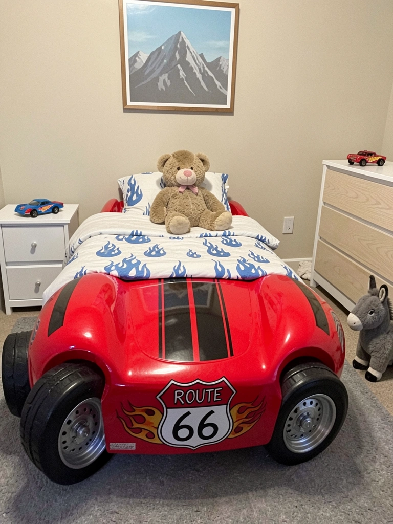 Carrinho de brinquedo vermelho ao lado de uma cama infantil em formato de carro