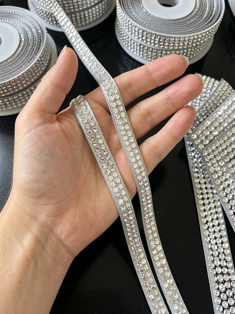 Rolos de fita de strass em várias larguras e uma folha plana sobre superfície clara