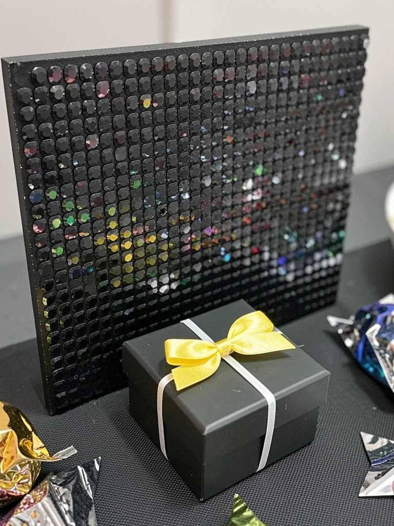 Mesa de festa decorada com painel de strass em formato de estrelas e lembrancinhas brilhantes ao redor