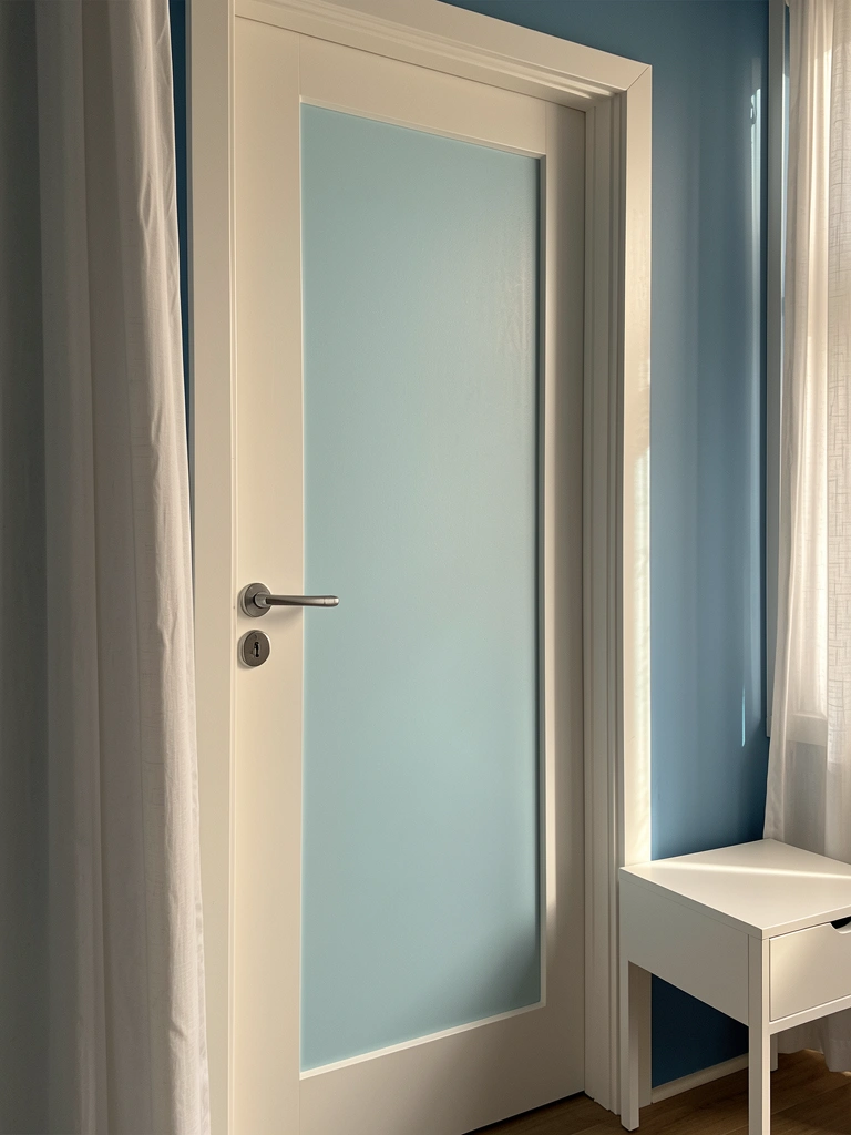 Porta de MDF azul claro com moldura branca, cortina branca ao lado e mesinha lateral minimalista, luz natural destacando a textura fosca.